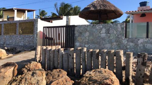 una cerca con rocas y un paraguas delante de una casa en B&B Beach House Pousada Exclusiva pés na água Pontal do Peba única em Alagoas en Pontal do Peba