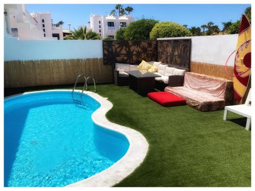 a backyard with a swimming pool and grass at Long Beach Surf House in Corralejo