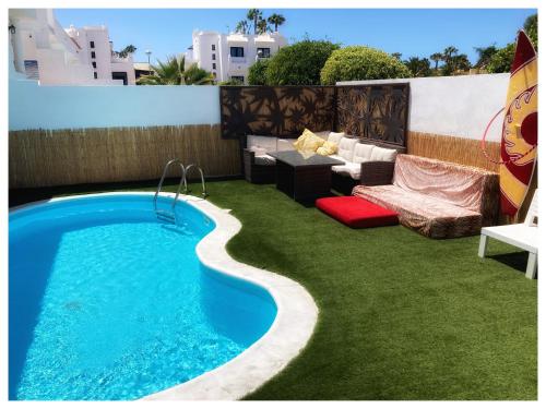 einen Hinterhof mit Pool und Gras in der Unterkunft Long Beach Surf House in Corralejo