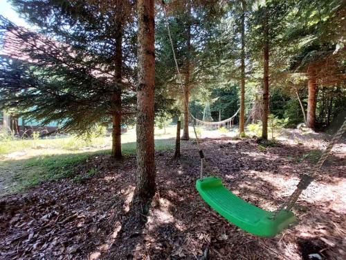 a green swing hanging from a tree in a park at Šumska bajka in Bajina Bašta