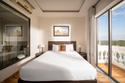 Un dormitorio con una gran cama blanca y una ventana en Viet Long Hoian Beach Hotel - STAY 24H en Hoi An