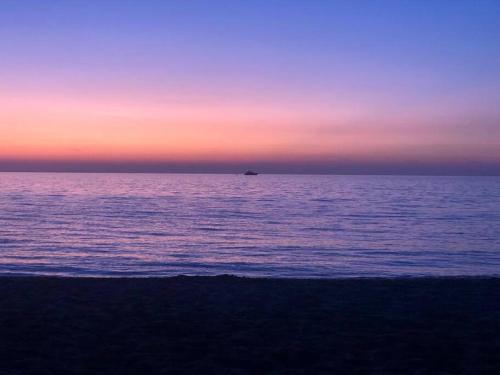 a sunset over the ocean with a boat in the distance at Relax Pine Villa Residence in Golem