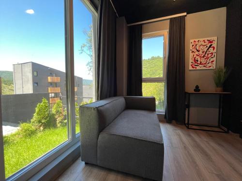 a living room with a chair and a large window at Mickitos Apartments - Mavrovo in Mavrovo