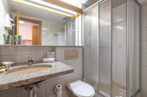 a bathroom with a toilet and a sink and a shower at Aktiv- und Genusshotel Alpenblick in Fiesch