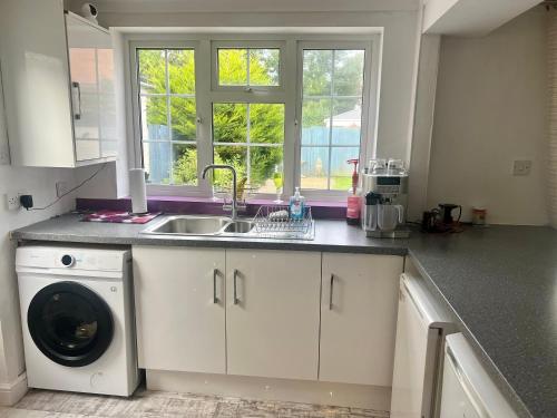 a kitchen with a sink and a washing machine at SuperKing Bed Free Parking Internet Garden Patio TV Quiet Close to main bus route B98 9NH in Beoley
