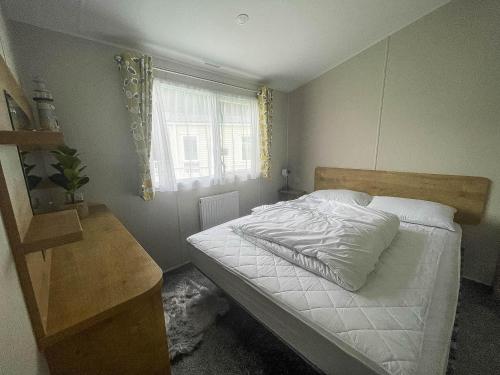 1 dormitorio con cama blanca y ventana en Beautiful 6 Berth Caravan With Decking In Norfolk Ref 89001mv en Belton