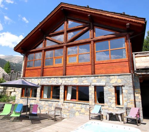 dom z krzesłami i basen przed nim w obiekcie Chalet le Soleil w mieście Montgenèvre