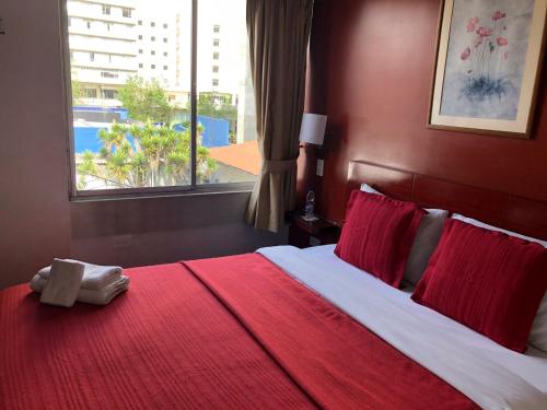 1 dormitorio con 1 cama grande con sábanas rojas y ventana en Filatelia Suites & Travel, en Quito
