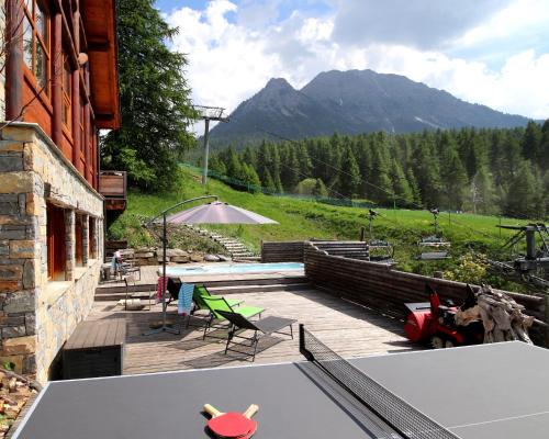 un patio avec une table et des chaises et une montagne dans l'établissement Chalet le Soleil, à Montgenèvre