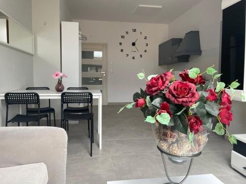 a vase filled with red roses in a living room at Apartament I w Centrum - Winda - 50 metrów od Starego Rynku in Kościerzyna