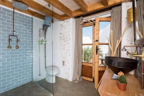 bagno con doccia in vetro e vasca nera di The Farm Lodge a Marbella