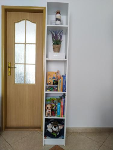 een boekenplank met boeken en speelgoed naast een deur bij príjemné ubytovanie in Košice