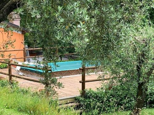 una terraza de madera con un banco azul sobre una valla en La casetta al lavatoio, en Borgo a Mozzano