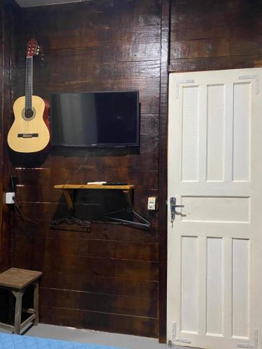 a room with a tv and a guitar and a door at Chalés Paradise in Atins