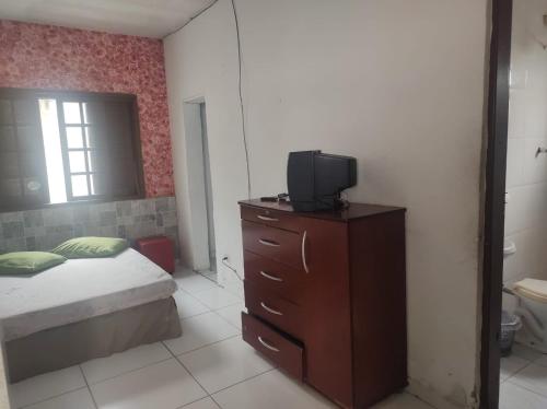 um quarto com uma cama e uma televisão numa cómoda em Pousada em Mongaguá Kali em Mongaguá