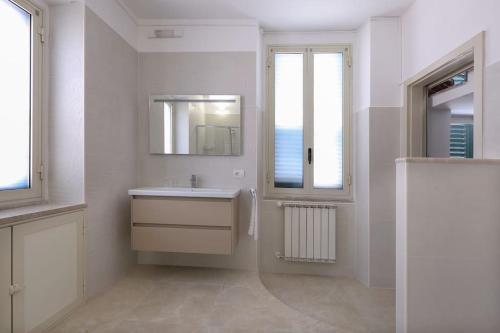 ein weißes Badezimmer mit einem Waschbecken und einem Spiegel in der Unterkunft Chez Pancrazio in Taormina