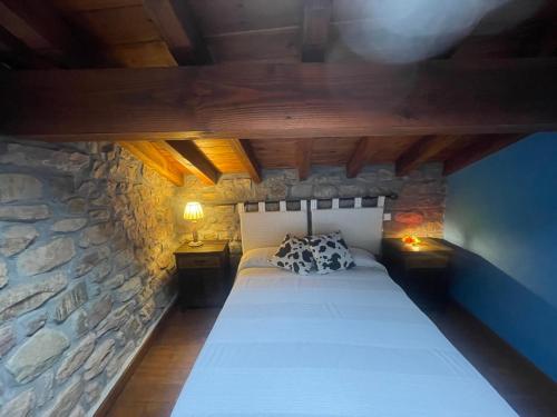 a bedroom with a bed in a stone wall at Casa de campo El Midiaju para 8 personas in Carmona