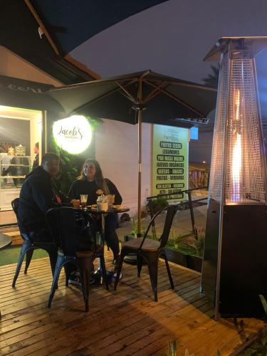 two people sitting at a table under an umbrella at Hostal restaurante Hidalgo in Punta de Choros