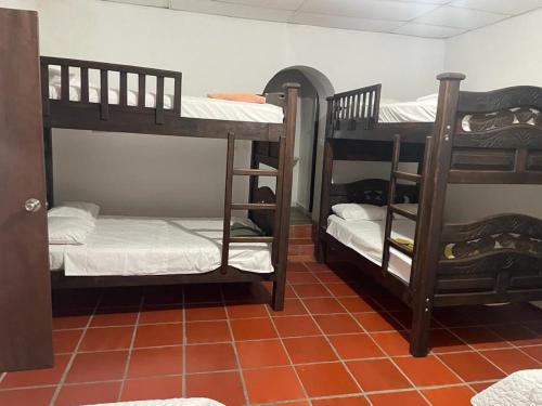 a room with two bunk beds and a tile floor at Hotel La Casona in Chinácota
