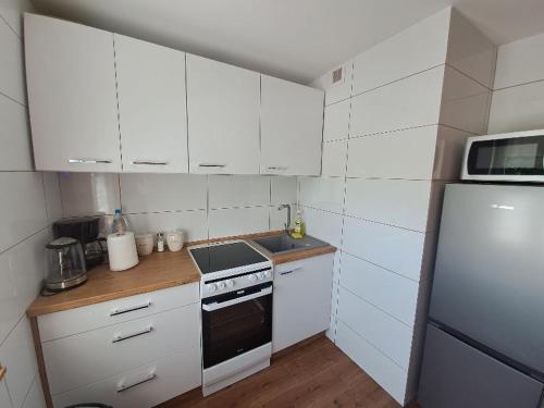 a small kitchen with white cabinets and a refrigerator at Apartament na Słoneczników in Tarnowskie Góry