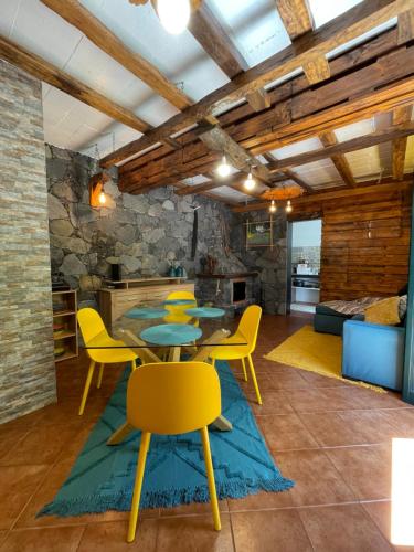 a living room with a table and yellow chairs at Casa da Nogueira in Porto Moniz