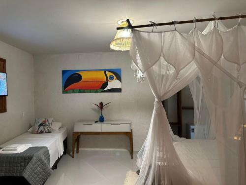 a bedroom with a bed and a table and a curtain at Pousada Preciosa do Arraial - com Natura e L'Occitane - recém inaugurada in Arraial d'Ajuda