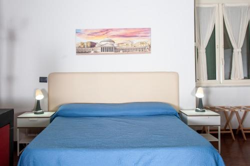 ナポリにあるPalazzo Carafa della Spina - Maison de Charmeのベッドルーム1室(青いベッド1台、テーブル2台、ランプ2つ付)