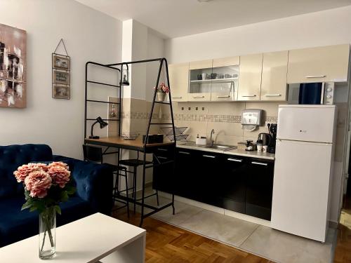eine Küche mit einem Kühlschrank und einem Tisch mit einer Vase aus Blumen in der Unterkunft The Luxe Loft apartment in Novi Sad
