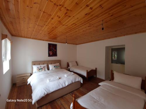 een slaapkamer met 2 bedden en een houten plafond bij Mountain Vista Guesthouse Shkafi in Shkodër