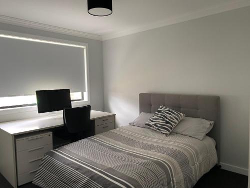Schlafzimmer mit einem Bett, einem Schreibtisch und einem Fenster in der Unterkunft Entire 4 bedroom home on Connolly in Bathurst in Kelso