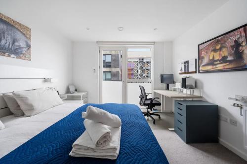 1 dormitorio con cama con sábanas azules y escritorio en Peachy Stays 2-Bedroom Amazing Flat With Balcony, en Londres