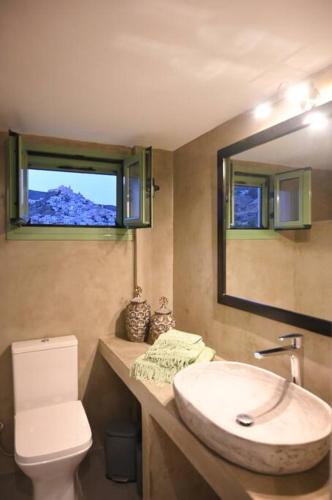 a bathroom with a sink and a toilet and a mirror at Απεριόριστη Θέα δίπλα στην πόλη in Ano Syros