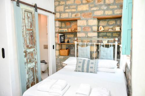 a bedroom with a bed and a brick wall at PYRGALI ΠΕΤΡΙΝΟ ΠΥΡΓΑΚΙ ΠΑΤΜΟΣ in Skala