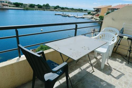 a table and chairs on a balcony overlooking the water at Appartement coup de coeur les pieds dans l'eau in Le Barcarès
