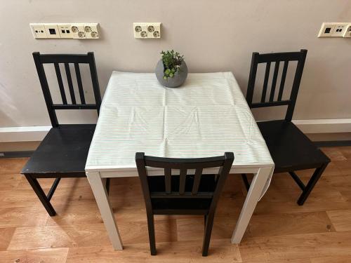 Pacific Hostel في فيلنيوس: طاولة بيضاء عليها كرسيين و مزهرية
