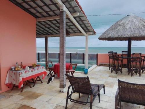 a patio with tables and chairs and a view of the ocean at B&B Beach House Pousada Exclusiva pés na água Pontal do Peba única em Alagoas in Pontal do Peba