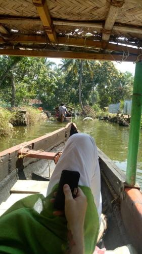 a person is sitting on a boat on a river at The Blues in Alleppey