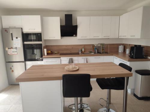 a kitchen with white cabinets and a wooden counter top at Villa Zen in Montbazin