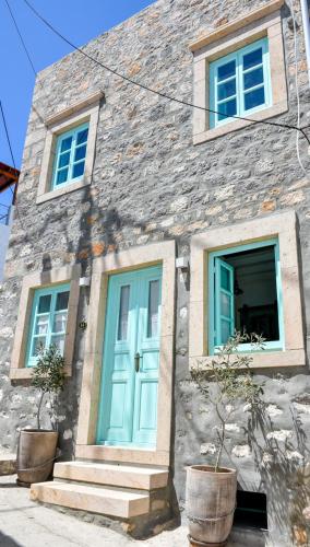 a stone house with a blue door and windows at PYRGALI ΠΕΤΡΙΝΟ ΠΥΡΓΑΚΙ ΠΑΤΜΟΣ in Skala