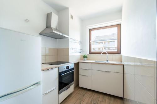 Una cocina con gabinetes blancos y un fregadero y una ventana. en Apartament Mierzeja Wiślana, en Sztutowo