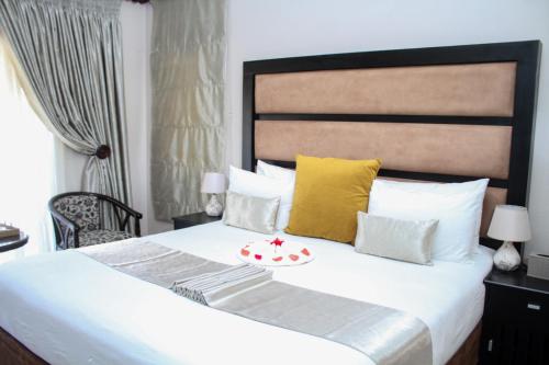 - une chambre dotée d'un grand lit avec des oreillers jaunes et blancs dans l'établissement SteyMorr Guesthouse, à Maun