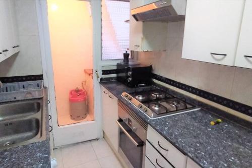 uma cozinha com um fogão e um lavatório em Beautiful private and exterior double room. em Esplugues de Llobregat