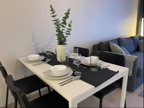 a white dining table with plates and glasses on it at Kaksio keskustassa ja rannan läheisyydessä in Hämeenlinna