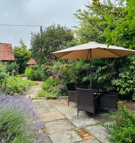 a table and chairs under an umbrella in a garden at Perfectly Positioned Hambleden House in Henley on Thames