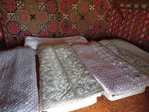 a group of blankets sitting on the floor in a room at Song Kol lake, Flex Travel yurt camp, horse riding in Song-Kul