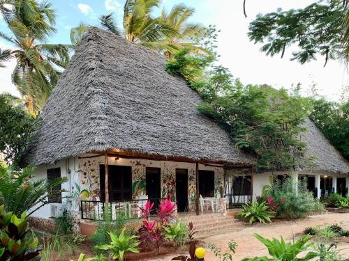 a small house with a thatched roof at Mambo Ocean Resort in Pwani Mchangani