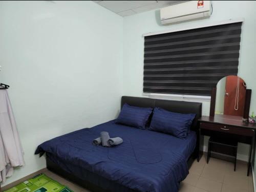 a bedroom with a bed with blue sheets and a desk at Andi Homestay in Sandakan