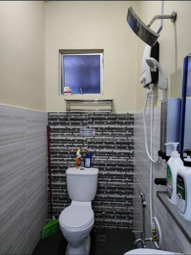 a bathroom with a white toilet and a window at Andi Homestay in Sandakan