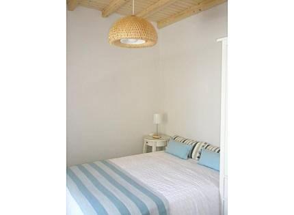 a white bedroom with a bed with blue pillows at Casa Azenhas in Azenhas do Mar