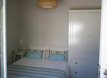 a white bedroom with a bed with blue pillows at Casa Azenhas in Azenhas do Mar